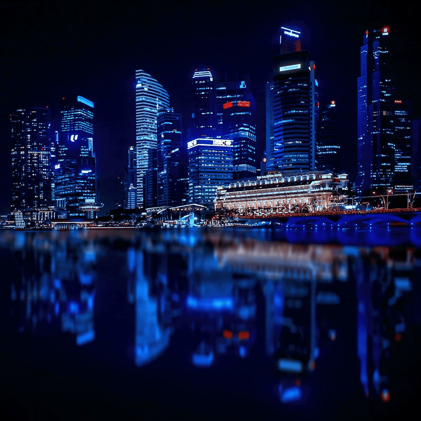 Eine Skyline bei Nacht bestehend aus mehreren Hochhäusern, die an einem Flussufer stehen.