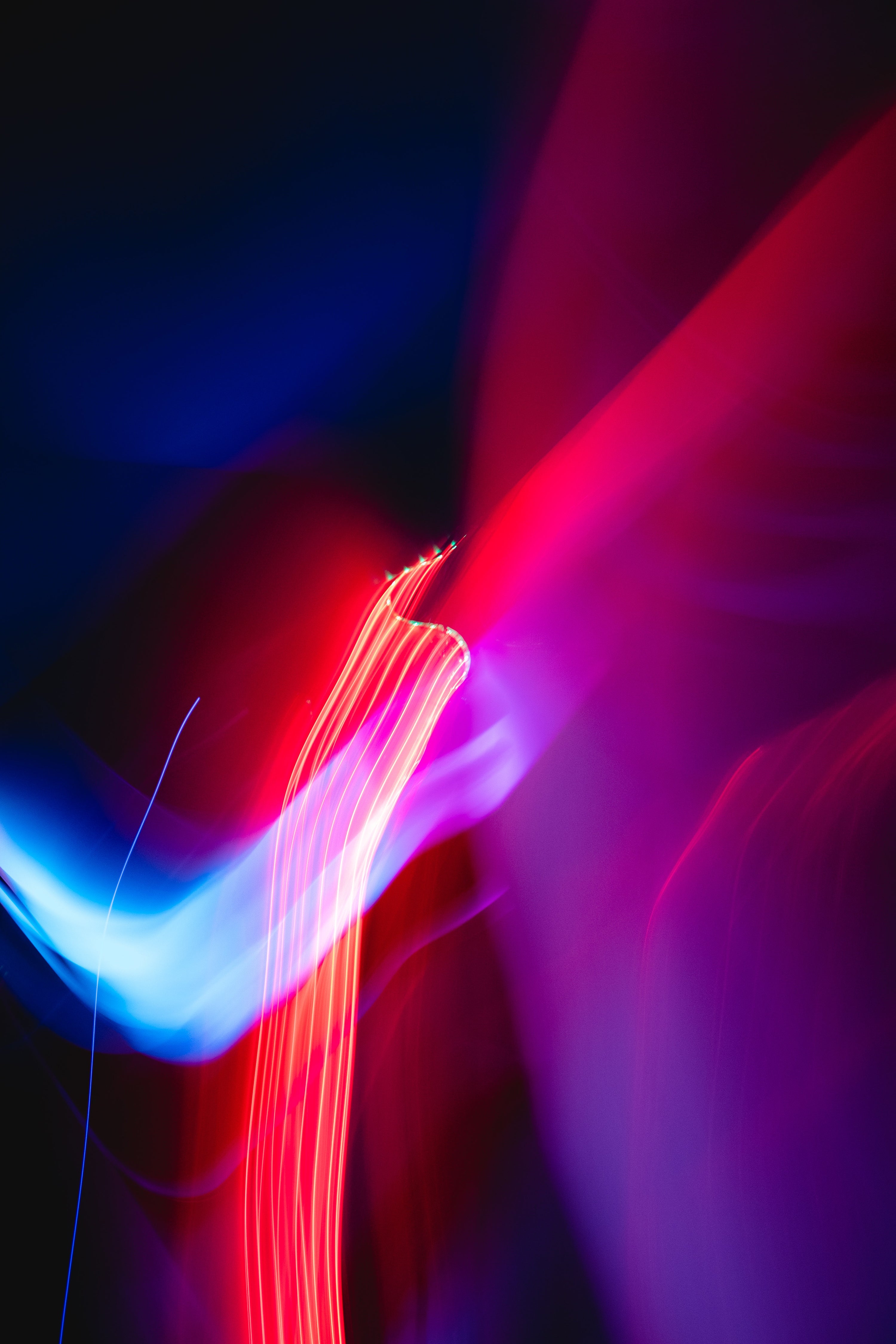 Abstraktes Bild aus blauen und roten Lichtstreifen auf dunklem Hintergrund.