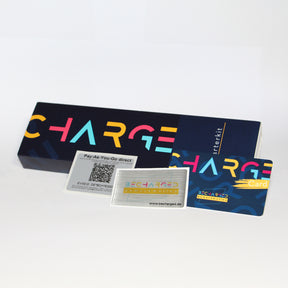 Ein länglicher, dunkelblauer Karton auf dem von links bis zur Mitte in großen gelben, roten und hellblauen Buchstaben "charge" steht. Ganz rechts steht von unten nach oben in weißen Buchstaben "Starterkit". Davor liegt von links nach rechts: ein QR-Code Label, ein Doming-Aufkleber mit dem becharged Logo und eine RFID-Karte. Die RFID-Karte ist wie der Karton dunkelblau mit dem bunten Schriftzug "charge card".